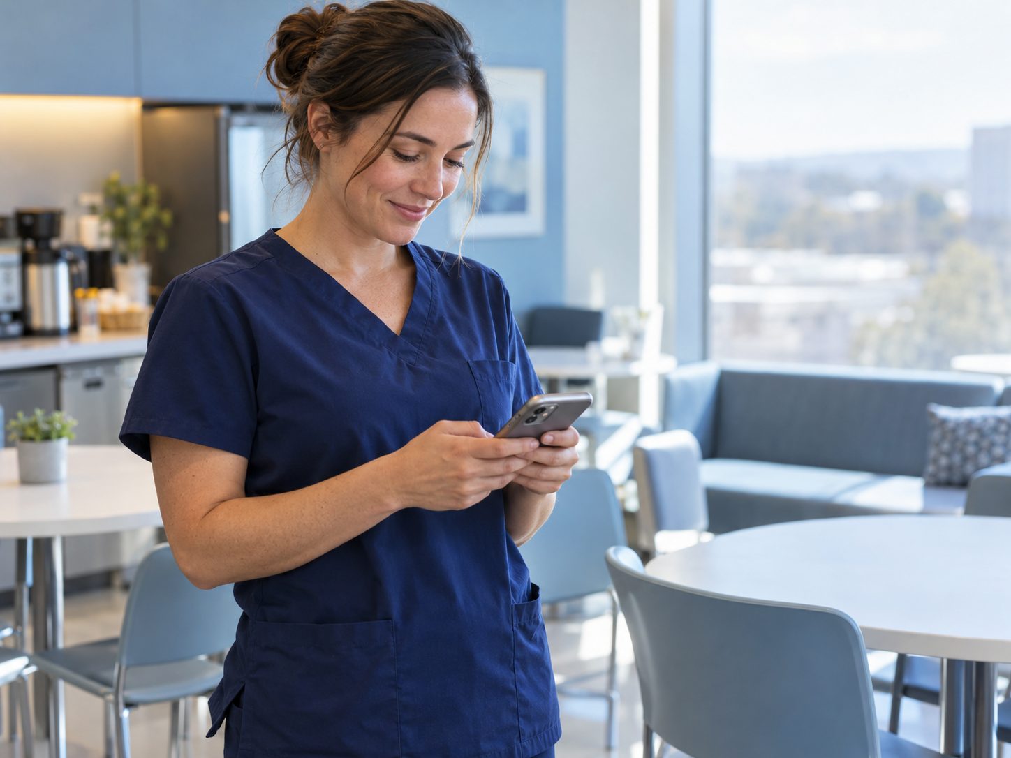 Nurse in navy scrubs checking her phone in a hospital break room